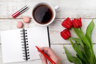 Kırmızı lale, kahve fincanı ve defter Beyaz ahşap masa üzerinde. Düz yatıyordu