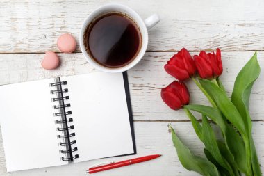 Kırmızı lale, kahve fincanı ve defter Beyaz ahşap masa üzerinde. Düz yatıyordu