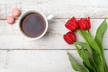 Kırmızı lale, kahve fincanı Beyaz ahşap masa üzerinde. Düz yatıyordu