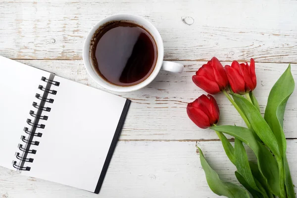 红色郁金香、 咖啡杯和笔记本在白色的木桌。平躺 — 图库照片