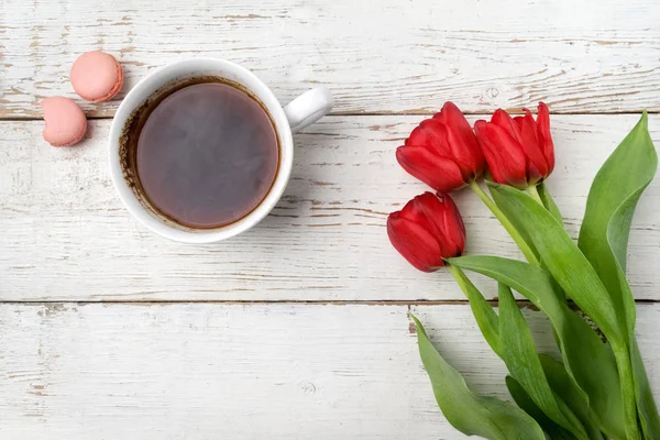 Czerwone tulipany, filiżanka kawy nad biały stół z drewna. Leżał z płaskim — Zdjęcie stockowe