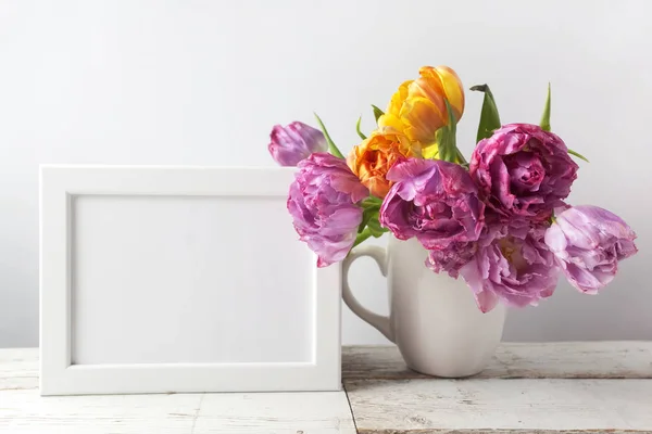 Bouquet di fiori di tulipano fresco e cornice fotografica vuota con spazio copia su sfondo di legno — Foto Stock