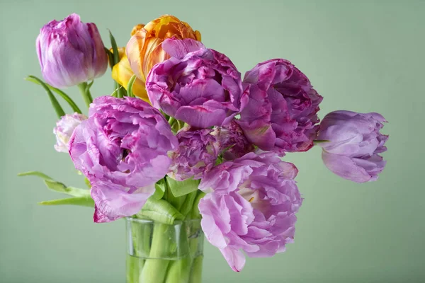 Svěží kytice z tulipánů ve váze na zeleném pozadí. Vintage stile — Stock fotografie