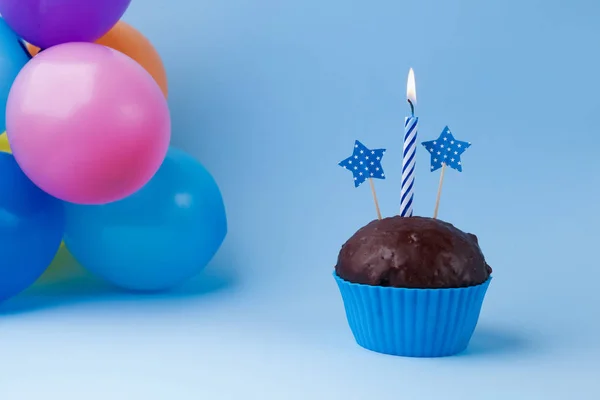 Кекс з барвистою свічкою на день народження та повітряними кулями — стокове фото