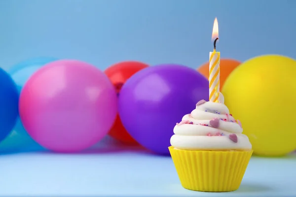 Cupcake avec bougie d'anniversaire colorée et ballons — Photo