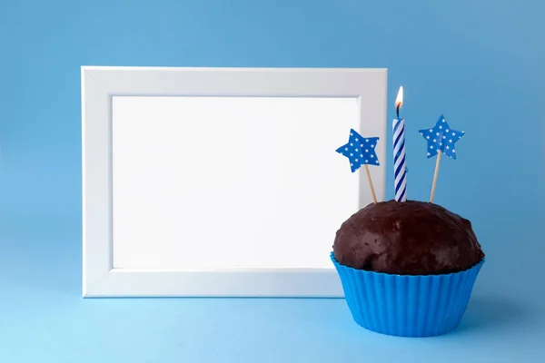 Gâteau avec bougie et cadre photo sur fond bleu gros plan — Photo