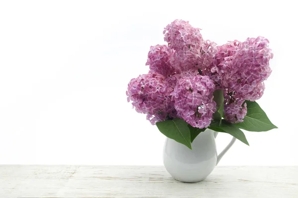 Bunch lilac in vase on wooden table — Stock Photo, Image