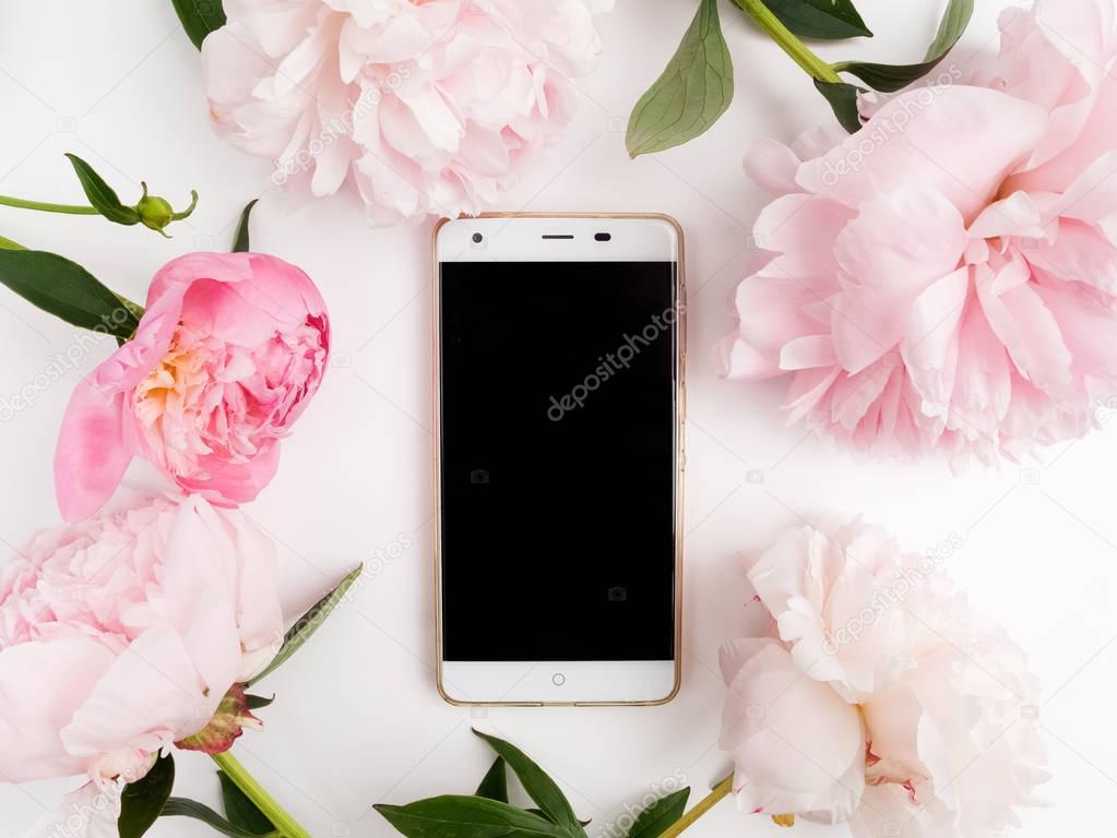 white phone with a clear screen on white background. peonies frame around. Flat lay. Top view