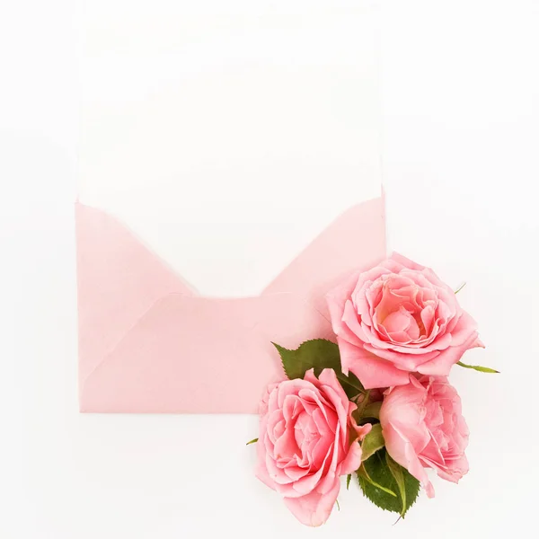 Enveloppe avec carte blanche et fond rose. Vue de dessus. Pose plate — Photo