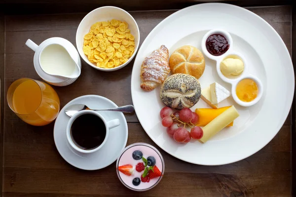 Pequeno-almoço continental rico. Croissants crostas franceses, muesli, muitas frutas doces e bagas, café quente para refeições matinais . — Fotografia de Stock