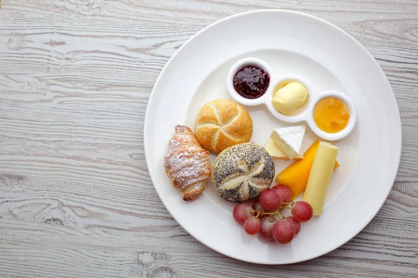 Rijk continentaal ontbijt. Franse knapperige croissants, muesli, veel zoete vruchten en bessen, hete koffie voor ochtend maaltijden. — Stockfoto