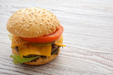 Peynir, et, domates ve soğan ve otlar ile hamburger. Ahşap arka plan üzerinde.