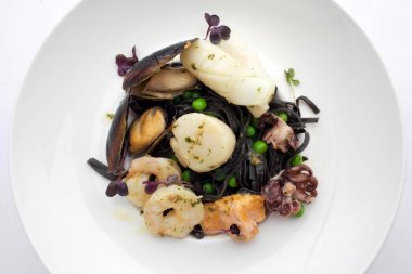 Siyah beyaz plaka üzerinde deniz ürünleri ile makarna. Midye ve karides. Üstten Görünüm