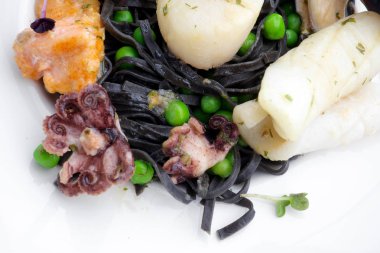 Siyah beyaz plaka üzerinde deniz ürünleri ile makarna. Midye ve karides. Üstten Görünüm