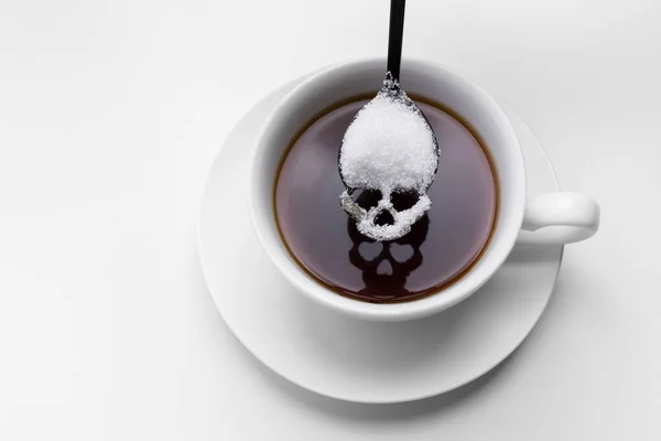 Unhealthy white sugar concept. Scull spoon with sugar and cup of black coffee — Stock Photo, Image