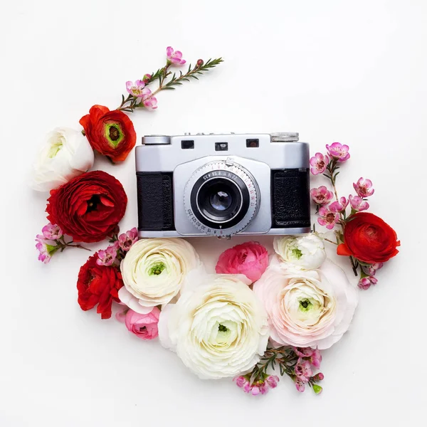 Vintage-Retro-Kamera, rotes und beiges Ranunkelblütenmuster auf weißem Hintergrund. flache Lage, von oben betrachtet dekoriertes Konzept. — Stockfoto