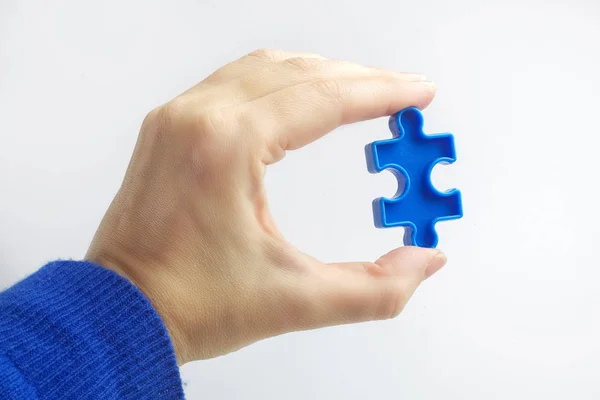 Mano che tiene pezzo puzzle blu su sfondo bianco. Concetto di consapevolezza dell'autismo — Foto Stock