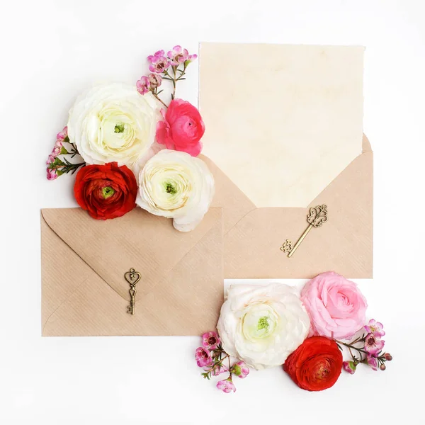 Plano tiro lay de carta e envelope de papel ecológico no fundo branco. Cartões de convite de casamento ou carta de amor com flores de ranúnculo. Dia dos Namorados ou outro conceito de férias. Vista superior — Fotografia de Stock