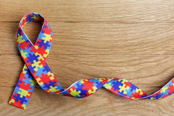 Wereld autisme bewustzijn en trots dag of maand met puzzel patroon lint op houten achtergrond. — Stockfoto