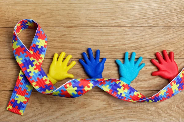 Conceito de consciência de autismo com mãos coloridas sobre fundo de madeira. Vista superior — Fotografia de Stock