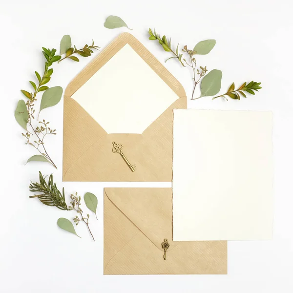 Επίπεδη θέσει shot επιστολή και οικολογικό χαρτί φακέλου σε άσπρο φόντο. Προσκλητήρια γάμου ή γράμμα αγάπης με φυτό. Ημέρα του Αγίου Βαλεντίνου ή άλλη έννοια διακοπών. Το Top view — Φωτογραφία Αρχείου