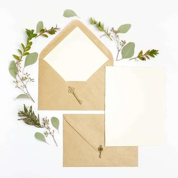 Plan plat de lettre et enveloppe en papier écologique sur fond blanc. Cartes d'invitation de mariage ou lettre d'amour avec plante. Saint-Valentin ou autre concept de vacances. Vue du dessus — Photo