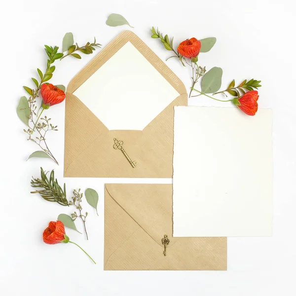 Flat lay shot of letter and eco paper envelope on white background. Wedding invitation cards or love letter with plant. Valentines day or other holiday concept. Top view