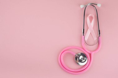 Pembe arka planda pembe kurdele ve steteskop, kadınlarda göğüs kanserinin sembolü, sağlık konsepti
