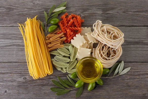 Diversi tipi di pasta sullo sfondo di legno. Spaghetti. Olio d'oliva . — Foto Stock