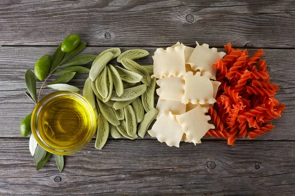 Spaghetti secchi in colori bandiera italiana e olio d'oliva su fondo legno — Foto Stock