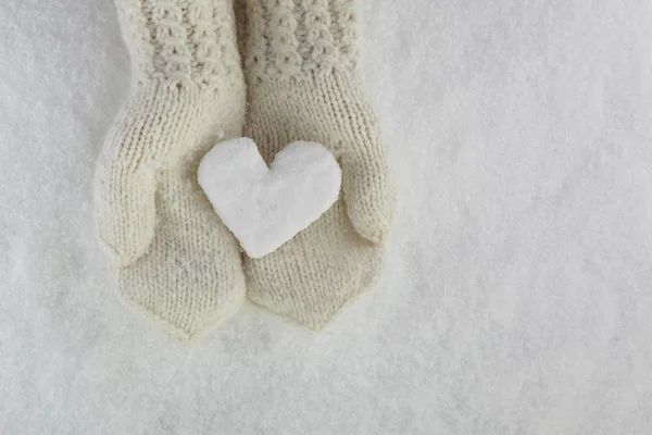 Снігове серце в руках з міттенсерами на білому сніговому тлі — стокове фото