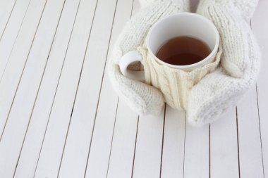 Beyaz ahşap arka planda kırmızı kalpli kadın elleri.