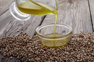 Cam kasede kenevir yağı ve ahşap arka planda tohumlar