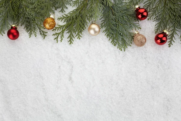 Kerstboom takken en kerstballen op sneeuw — Stockfoto