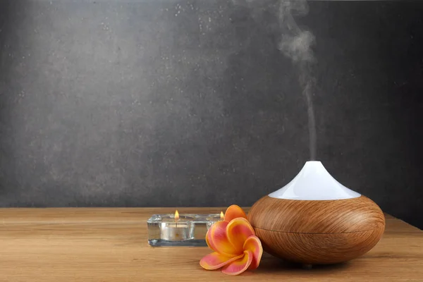 Difusor de óleo de aroma, velas e flores na mesa de madeira — Fotografia de Stock