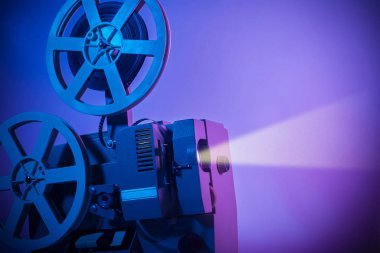Eski moda projektör karanlık bir odada film yansıtıyor.