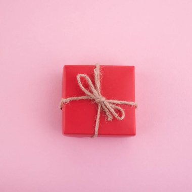 Pembe arka planda kırmızı hediye kutusu. Düz yatıyordu. Üst görünüm