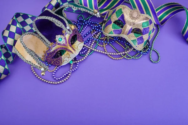 Colorful Mardi Gras mask on purple background with beads and ribbons. Top view. Copy space — Stock Photo, Image