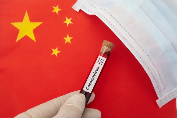 Coronavirus outbreak concept. Nurse hand holding test tube with infected blood over Chinese flag. — Stock Photo, Image