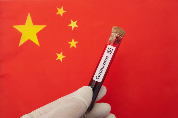 Coronavirus outbreak concept. Nurse hand holding test tube with infected blood over Chinese flag. — Stock Photo, Image