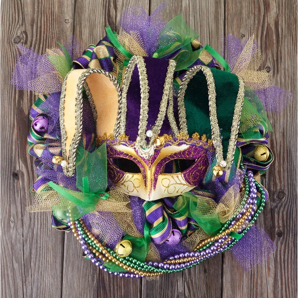Mardi gras wieniec na starych drewnianych drzwiach z maską Mardi Gras. — Zdjęcie stockowe