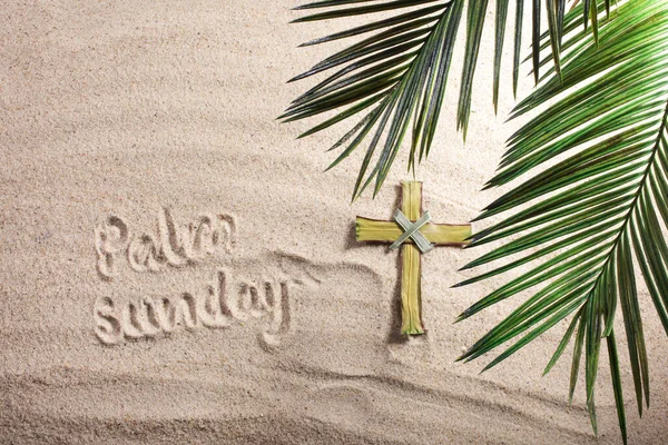 Cross and Palm Tree Leaves on sand. Palm sunday concept. Top view — Stock Photo, Image