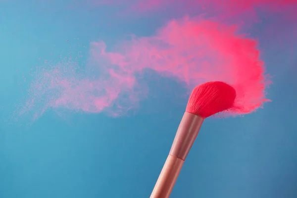 Close-up foto van twee professionele make-up penselen met roze poeder in beweging op blauwe achtergrond — Stockfoto