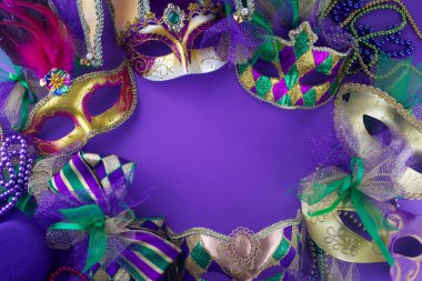 Bir grup Mardi Gras maskesi mor arkaplan üzerinde kopyalama alanı olan bir çerçeve oluşturuyor