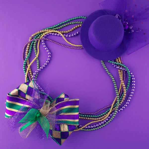 Mardi Gras-pärlor och mask att göra en ram med kopia utrymme på en lila bakgrund — Stockfoto