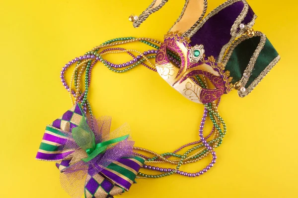 Mardi Gras pärlor och mask gör en ram med kopieringsutrymme på en gul bakgrund — Stockfoto