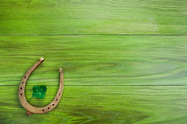 Hoefijzer en klaver op groene houten ondergrond. Groene klavertje vier. Sint Patricks dag symbool. — Stockfoto