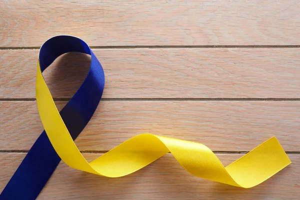Fita azul e amarela sobre fundo de madeira. Dia Mundial da Síndrome de Down. Fita de sensibilização . — Fotografia de Stock