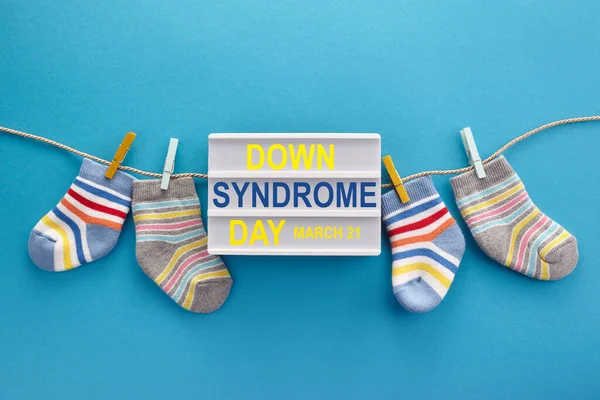 World Down syndrome day background. Down syndrome awareness concept. Socks and lightbox on blue background — Stock Photo, Image