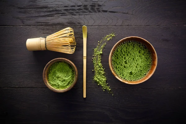 Matcha-Puder. Bio-grüner Matcha-Tee Zeremonie. Gesundes Getränk Traditionelles japanisches Getränk auf schwarzem Holzgrund — Stockfoto